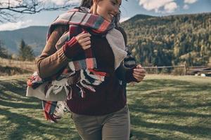 Happiness highlights her beauty. Attractive young woman smiling while running on the valley in mountains outdoors photo