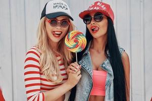 Sweet as lollipop. Seductive young women holding big lollipop and looking at camera while standing outdoors photo