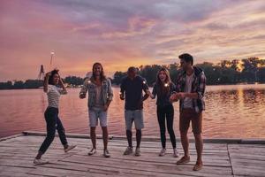 Pure happiness. Full length of young people in casual wear smiling and holding sparkers while standing on the pier photo