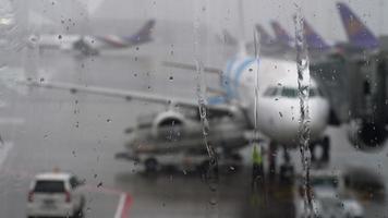 tempesta in aeroporto. vista dell'aereo attraverso gocce di pioggia e ruscelli. temi del tempo e del volo in ritardo o cancellato. video