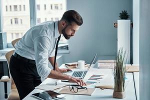 Modern young man in shirt and tie working with documents in office photo