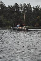 Moments of joy. Beautiful young couple enjoying romantic date and smiling while rowing a boat photo