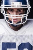 Fearless warrior.  Portrait of American football player looking at camera  while standing against black background photo