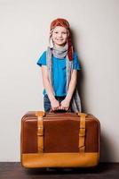 Ready to big travel. Happy little boy in pilot headwear and eyeglasses carrying a big briefcase and smiling photo