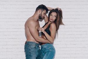 siempre juntos. hermosa joven pareja abrazándose mientras está de pie contra la pared de ladrillo foto