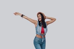 Attractive stylish young woman looking away and smiling while standing against grey background photo