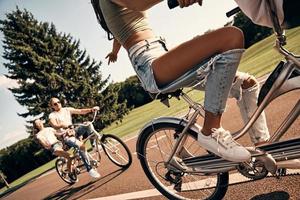Doing what they love. Group of happy young people in casual wear cycling together while spending carefree time outdoors photo