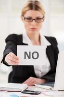 Rejection. Serious mature woman in formalwear saying no to you while stretching out a paper photo