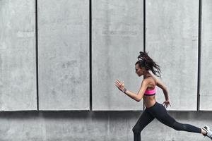 Ready to break any record. Modern young woman in sports clothing jumping while exercising outdoors photo