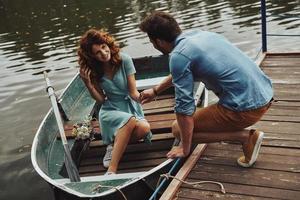 cita romántica. feliz pareja joven preparándose para remar un bote mientras disfruta de su cita al aire libre foto