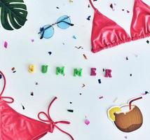 Summer is here High angle shot of bikini, eyewear, coconut and flower lying against white background photo