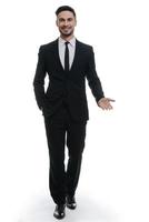 Open to new ideas. Full length of handsome young man in full suit holding one hand in pocket and looking at camera while standing against white background photo