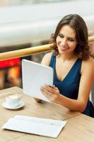 Coffee break. A beautiful young woman taking a break while working with digital tablet in restaurant photo