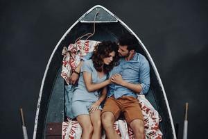 Always protecting her. Top view of beautiful young couple embracing while lying in the boat photo