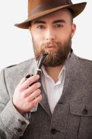 Man with a smoking pipe. Portrait of handsome young man in formalwear holding a smoking pipe and smiling at camera photo