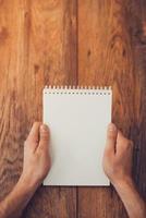 Copy space for your text . Top view of man holding note pad upon the wooden desk photo