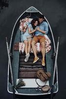 momentos de paz juntos. vista superior de una hermosa pareja joven abrazándose y sonriendo mientras yacía en el bote foto
