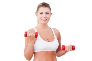 Mature woman with dumbbells. Attractive mature woman in sports clothing training with dumbbells and smiling while standing isolated on white photo