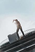 Staying hydrated. Full length of young woman in sport clothing drinking water while standing outdoors photo