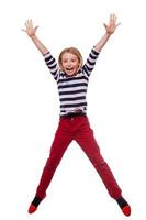 Carefree child. Full length of happy little girl jumping while standing isolated on white photo