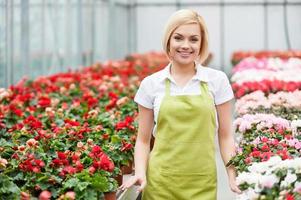 Women in flowers. Beautiful blond hair woman standing in flower bed and smiling photo
