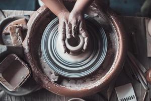 primer plano sobre la creatividad. vista superior del alfarero haciendo vasija de cerámica en la rueda de alfarería foto
