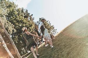 nada más que familia. vista trasera completa de una familia joven de tres tomados de la mano mientras corre al aire libre foto