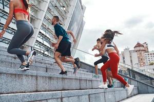 Group of young people in sports clothing jogging while exercising on the stairs outdoors photo