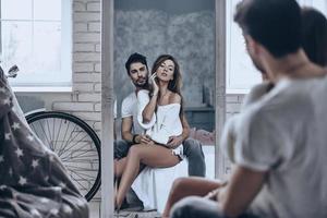 Love reflection. Rear view of beautiful woman looking at her reflection in the mirror while sitting in her boyfriends arms photo