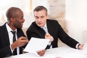 Contract on good conditions. Two cheerful business people in formalwear discussing something and pointing a paper photo