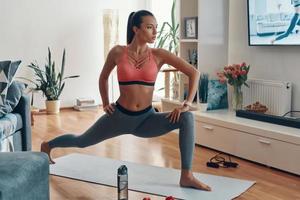 Attractive fit young woman in sports clothing working out while spending time at home photo