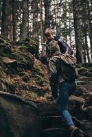 Getting in touch with nature. Young couple holding hands and moving up while hiking together in the woods photo
