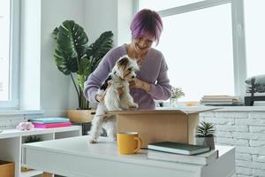 bella mujer joven y un perrito lindo mirando dentro de una caja foto