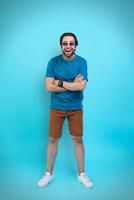 Excited young man in casual clothing gesturing and smiling while standing against yellow background photo