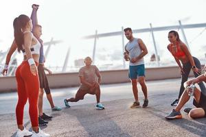 Group of people in sports clothing warming up and stretching outdoors photo