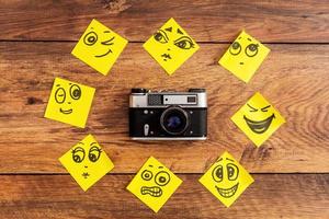 Emotional circle. Close-up of retro camera surrounding by adhesive notes with drawings on them photo