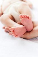 diminutos pies pequeños. primer plano de padre sosteniendo una pequeña mano de su pequeño bebé foto