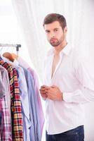 Man wearing white shirt. Confident young man dressing up white shirt and looking at camera photo