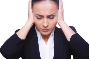 Stressed businesswoman. Frustrated young woman in formalwear covering ears with hands and keeping eyes closed while standing isolated on white photo