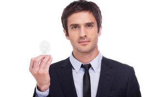 Businessman with light bulb. Cheerful young man in formalwear stretching out hand with light bulb and smiling while standing isolated on white background photo