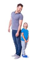 Cheerful father and son. Father and son standing back to back and looking at each other while standing isolated on white photo