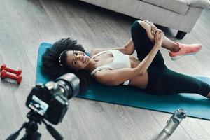 Top view of young fit African woman working out and smiling and shows exercising while making social video photo