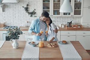 hermosa pareja joven preparando el desayuno juntos mientras pasan tiempo en la cocina doméstica foto