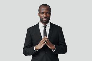 Handsome young African man in formalwear looking at camera while standing against grey background photo