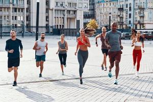 toda la longitud de la gente con ropa deportiva trotando mientras hace ejercicio en la acera al aire libre foto