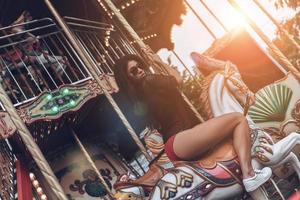 Just for fun. Attractive young mixed raced woman in red bikini riding merry-go-round photo