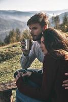 disfrutando el tiempo juntos. hermosa pareja joven tomando café por la mañana mientras pasa tiempo sin preocupaciones en las montañas foto