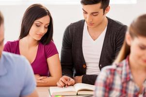 estudiando juntos. estudiantes alegres que estudian juntos mientras están sentados en el aula foto