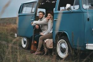 Just stopped to enjoy the view.  Beautiful young couple looking away and smiling while sitting in blue retro style mini van photo