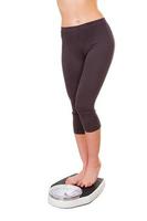 control de peso. imagen recortada de una mujer joven con ropa deportiva parada en una báscula foto